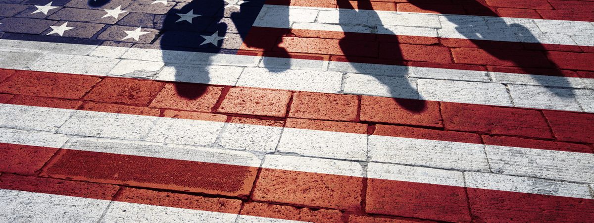 An American flag painted on a brick road with people’s silhouettes in El Paso.
