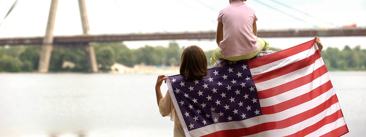 A family standing in front of a river holding an American flag behind their backs in El Paso.