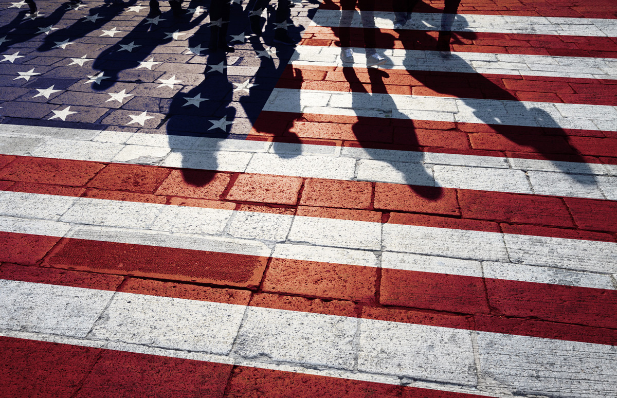 An American flag painted on a brick road with people’s silhouettes in El Paso.